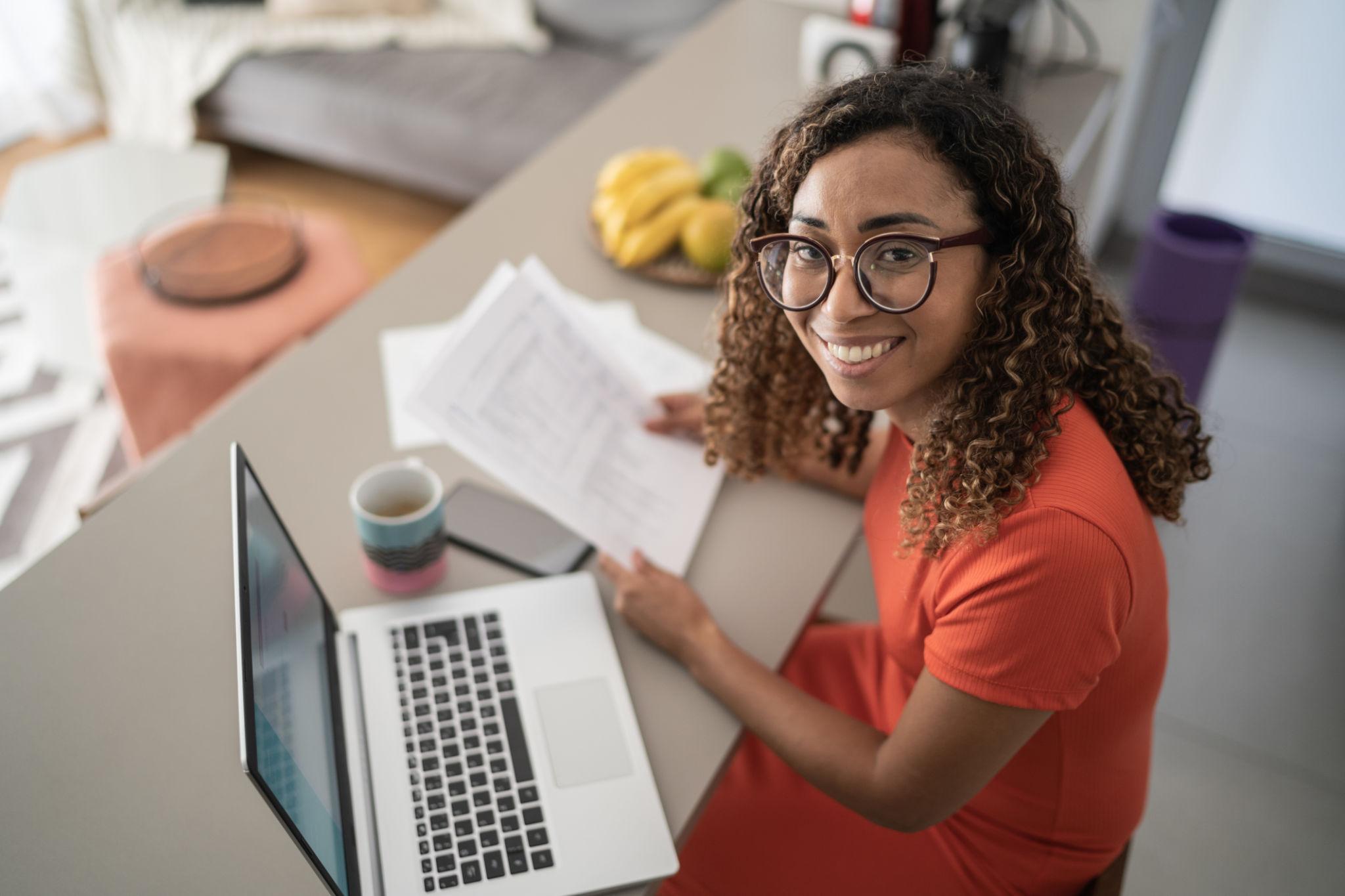 Homem organizando contas e utilizando notebook no sofá de casa